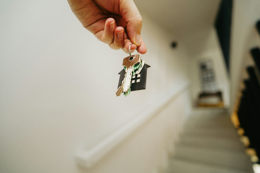 Persona con llaves frente a una vivienda, imagen ilustrativa de una compraventa