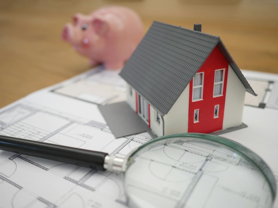 Casa en miniatura junto a una lupa, imagen ilustrativa de la revisión registral de un inmueble